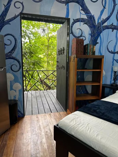Charming forest-themed bedroom with balcony views into lush greenery