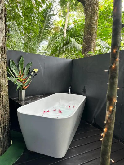 Private open-air soaking tub surrounded by lush tropical greenery