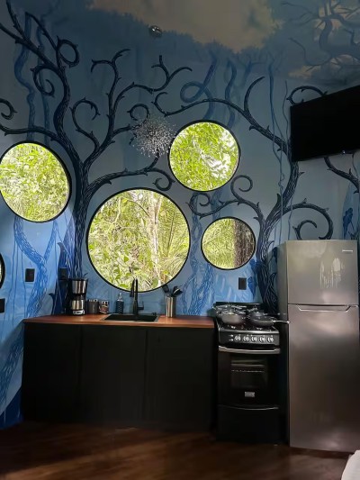 Artistic kitchen with round jungle-view windows and a magical, nature-inspired design