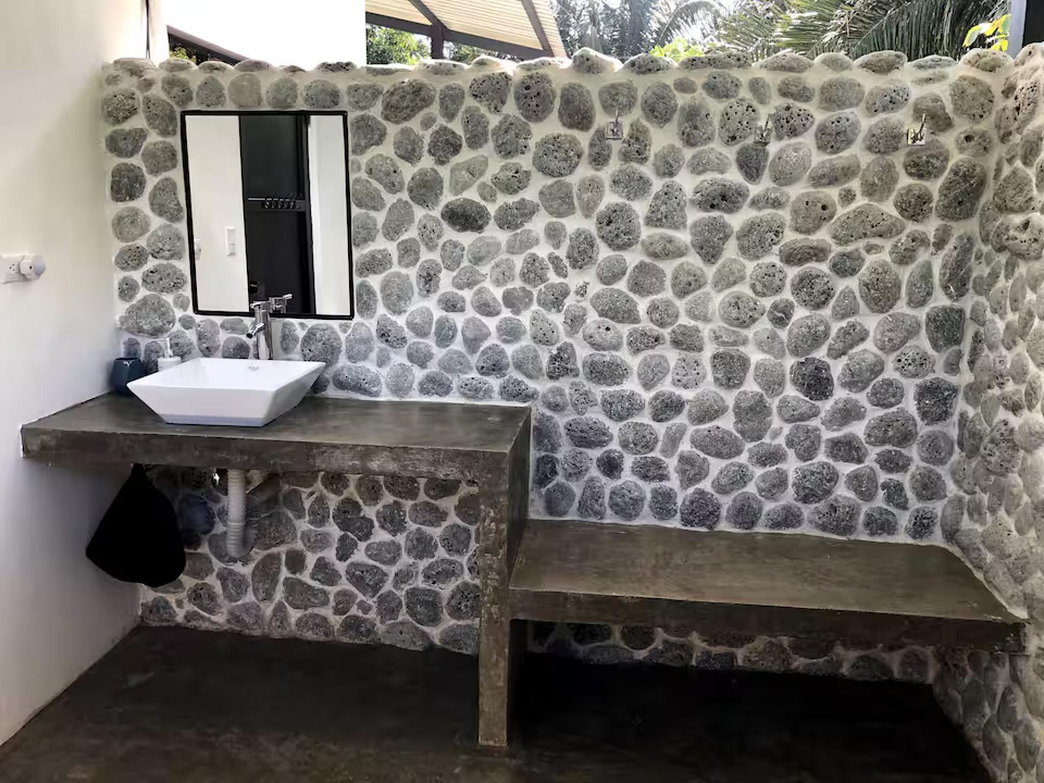 Rustic open-air bathroom with stone walls and a spa-like tropical feel