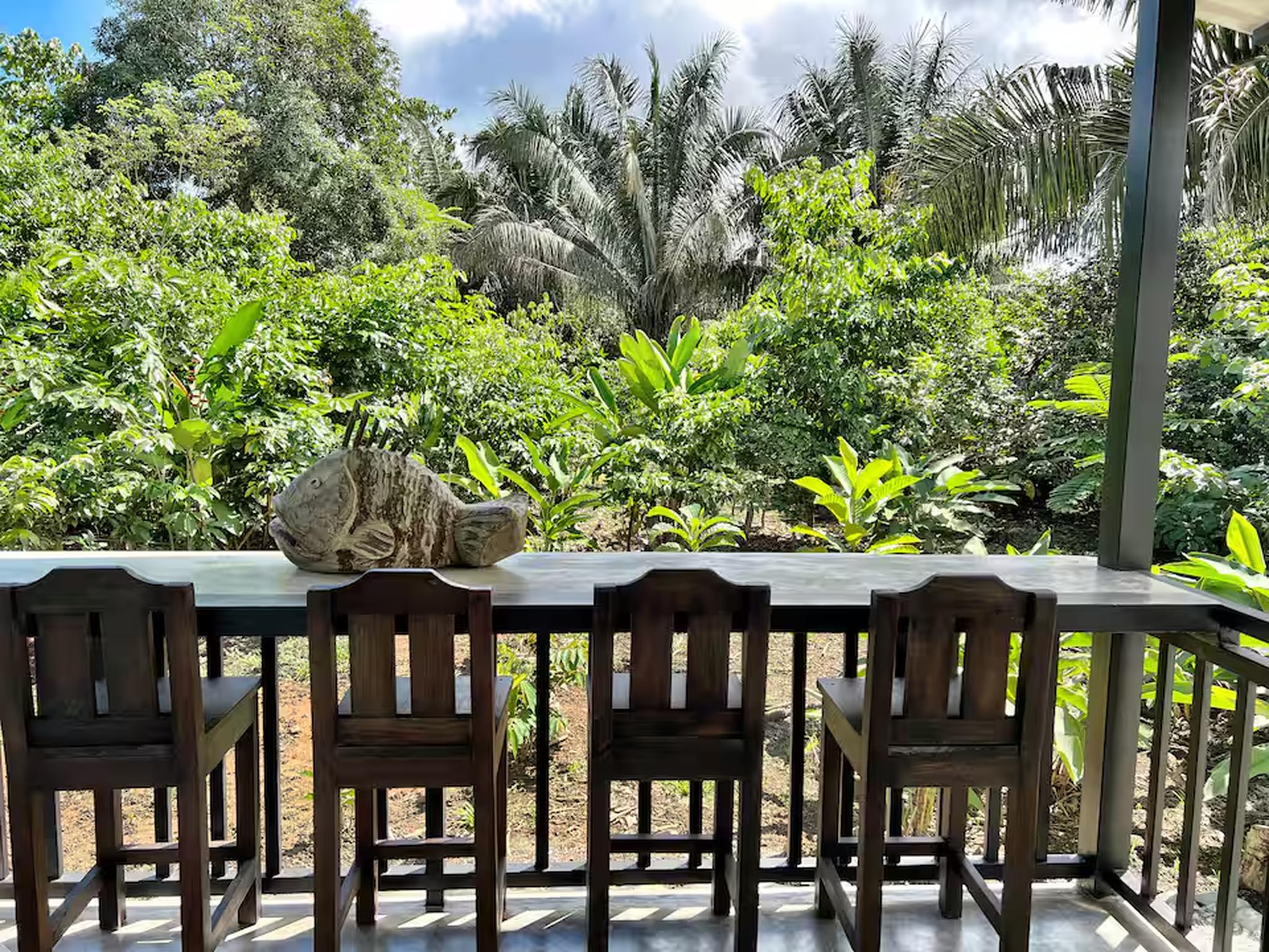 Covered outdoor bar seating with serene tropical garden views