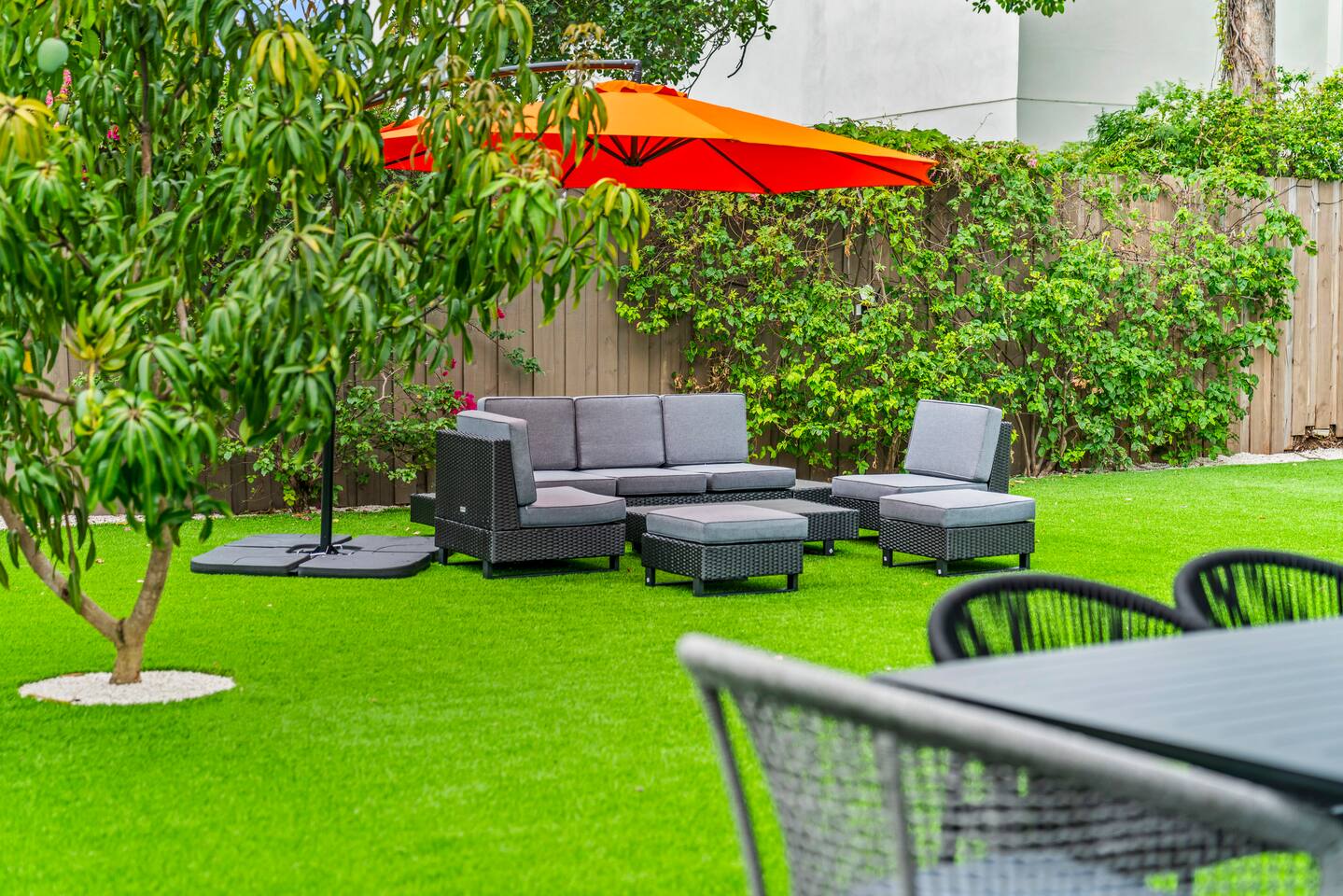 Designed for both relaxation and entertaining, the spacious backyard features lush lawns, shaded seating, and charming outdoor gathering spaces.