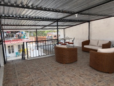 Spacious covered rooftop terrace with cozy seating and open-air views