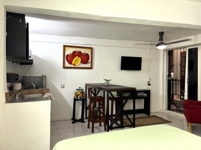 Cozy studio with kitchenette, dining nook, TV, and balcony access