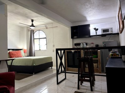 Cozy studio with arched window, kitchenette, and high-top dining area