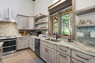 Sleek modern kitchen featuring wooded views and elegant finishes — a beautifully appointed space perfect for cooking and gathering, with nature as the backdrop throughout your stay.