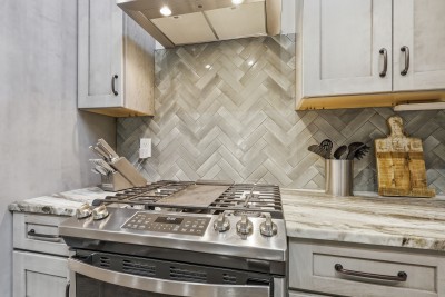Modern chef’s kitchen featuring a gas range and elegant herringbone backsplash — a beautifully appointed space for cooking up memorable meals during your mountain stay.