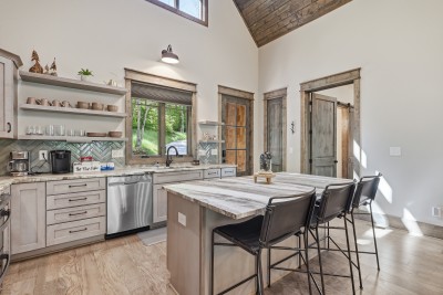 Rustic-modern kitchen featuring vaulted ceilings, island seating, and a bright, open feel — a stylish and inviting space for cooking, gathering, and enjoying meals together.
