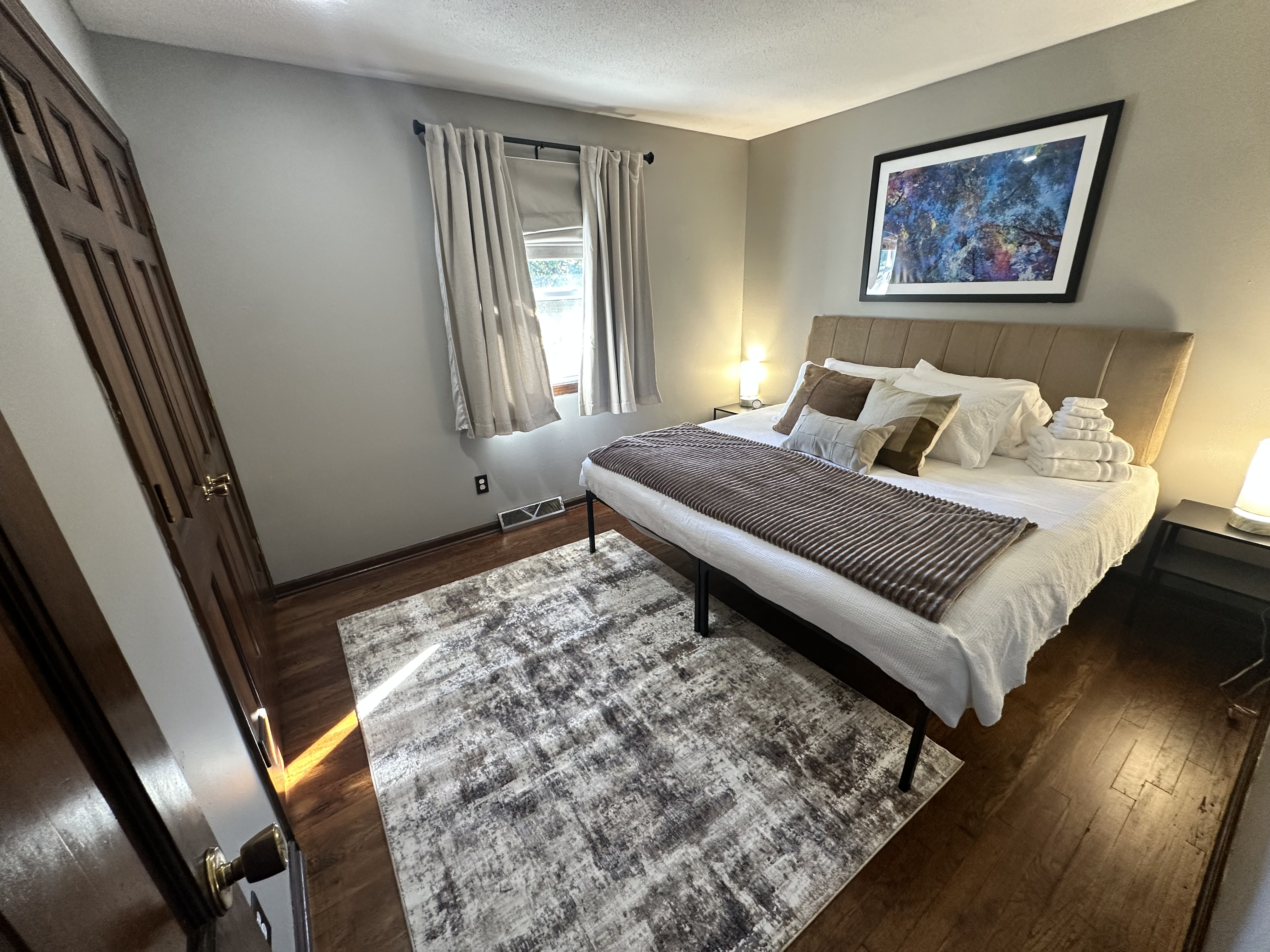 Cozy, light-filled bedroom with plush bed, hardwood floors & soft decor