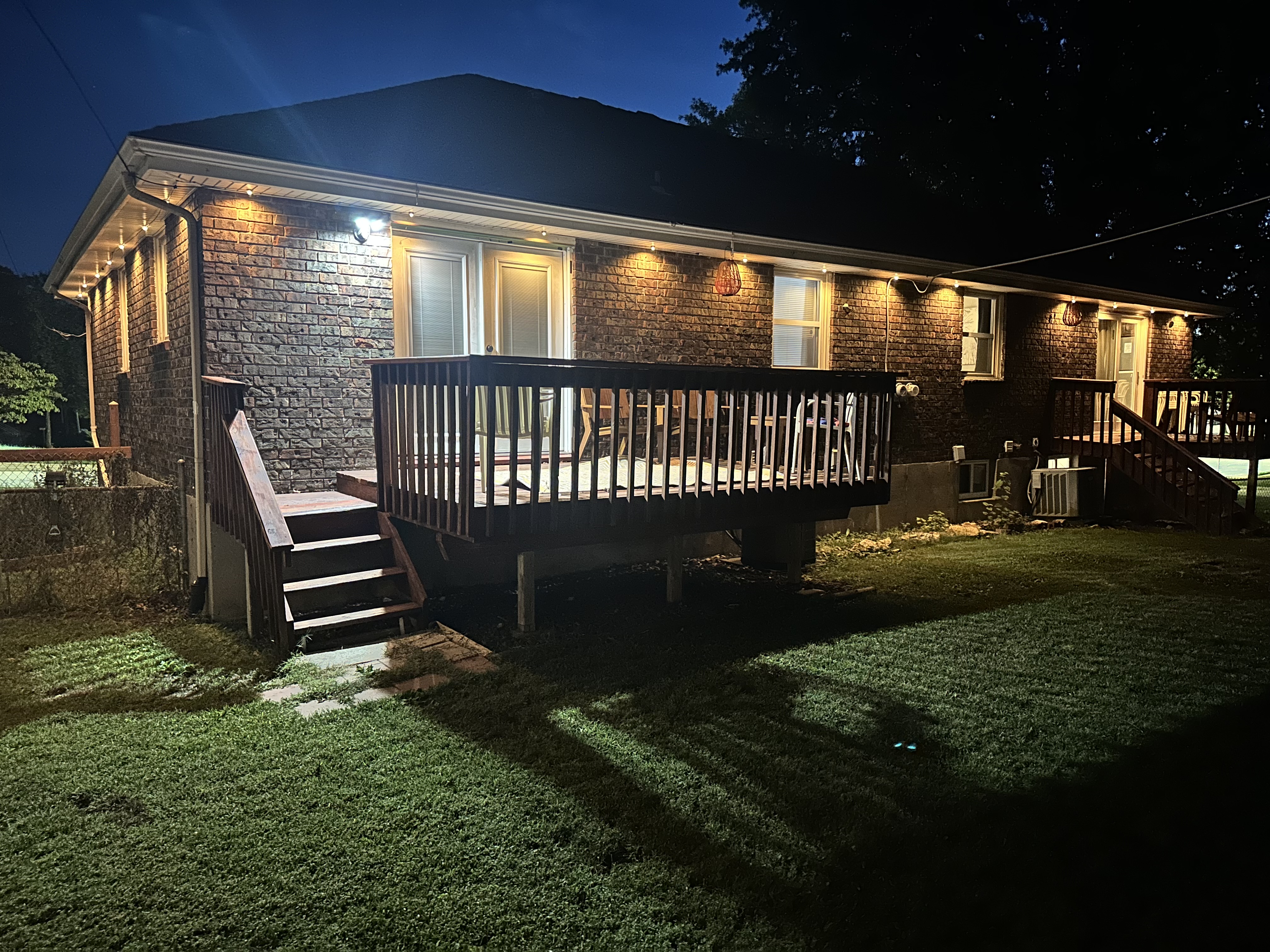 Warmly lit brick home with raised deck and spacious backyard
