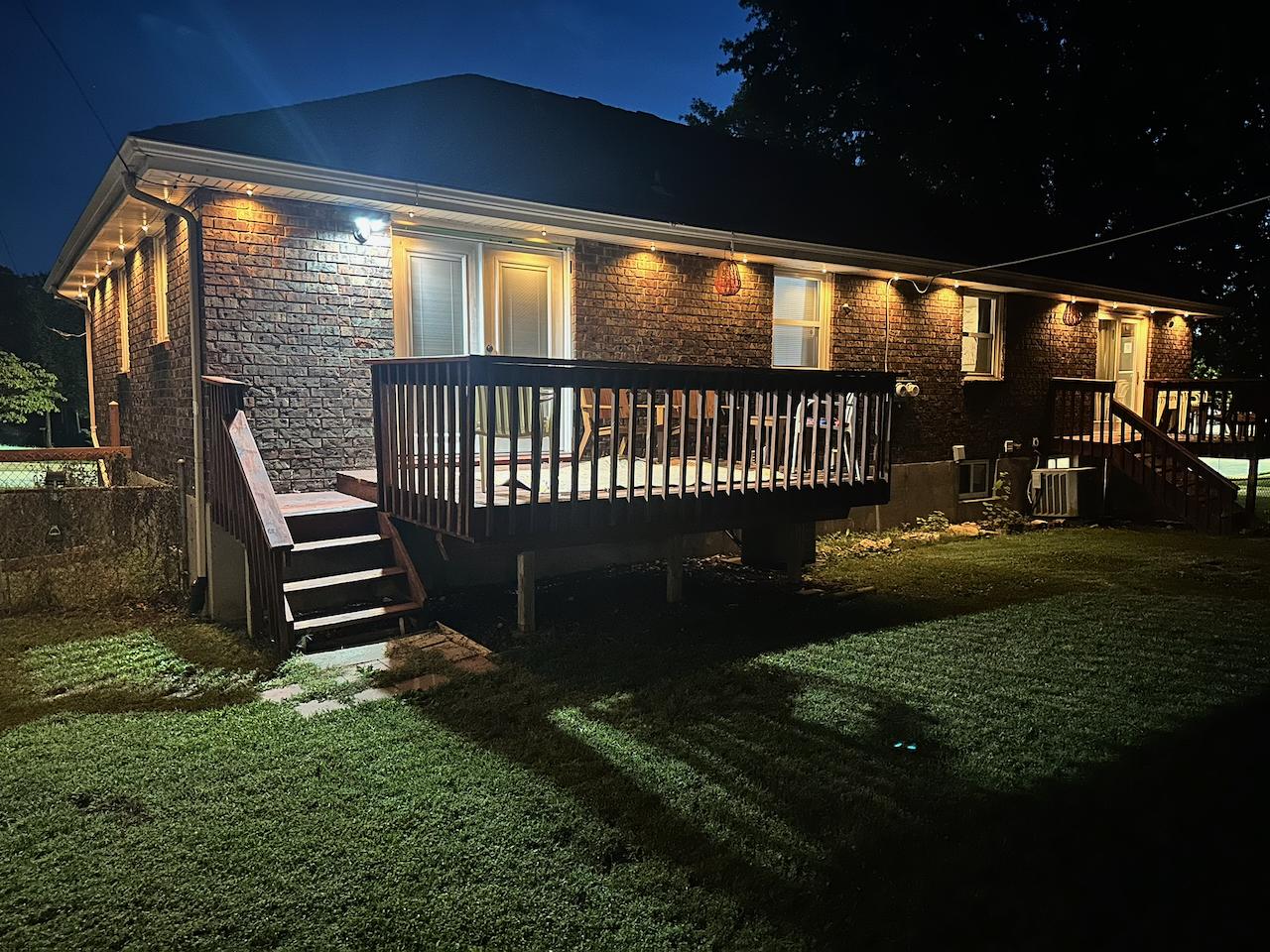 Well-lit backyard deck with seating and a spacious grassy yard