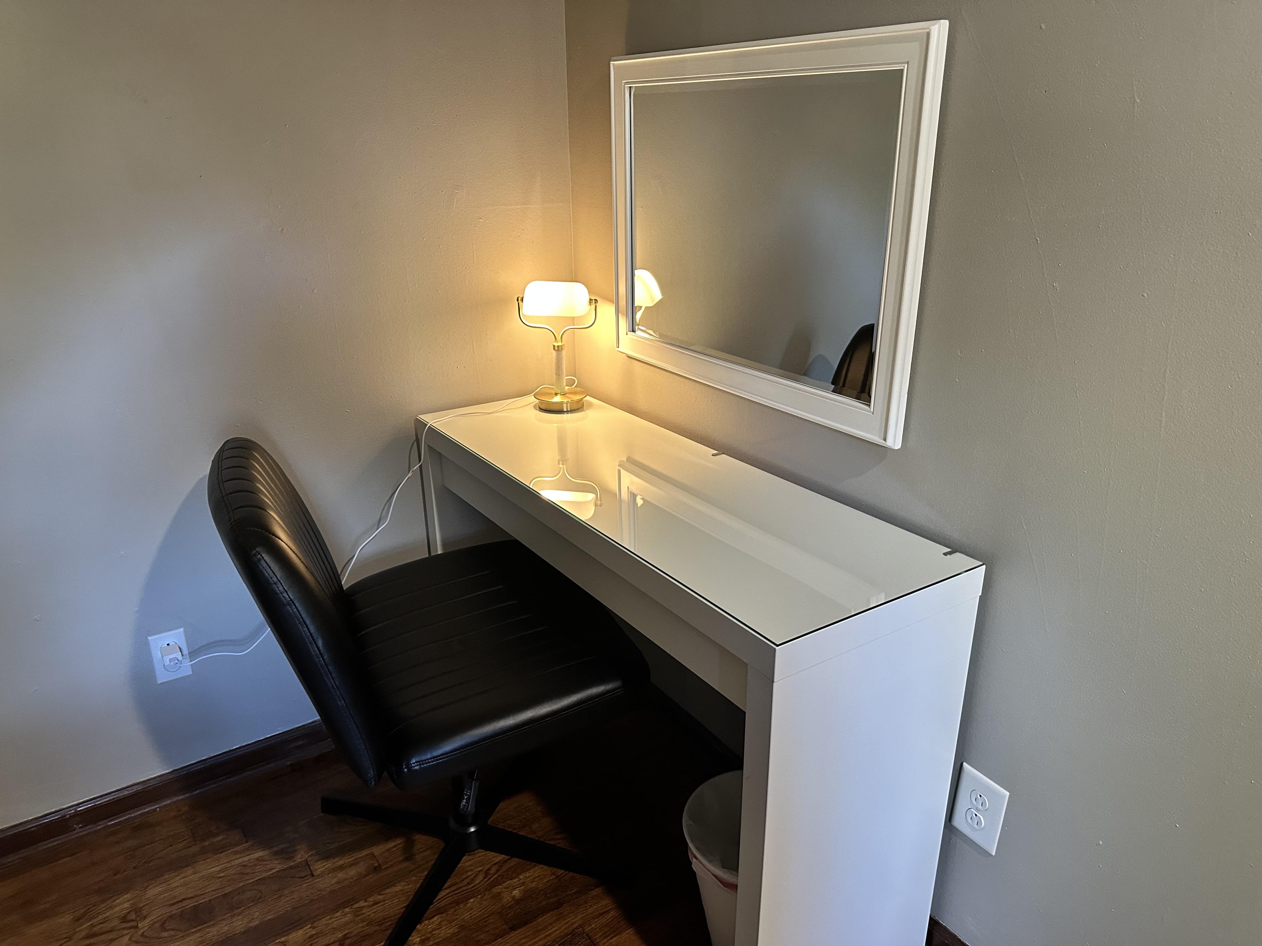 Bright vanity/work desk with mirror, soft lighting, and comfy seating