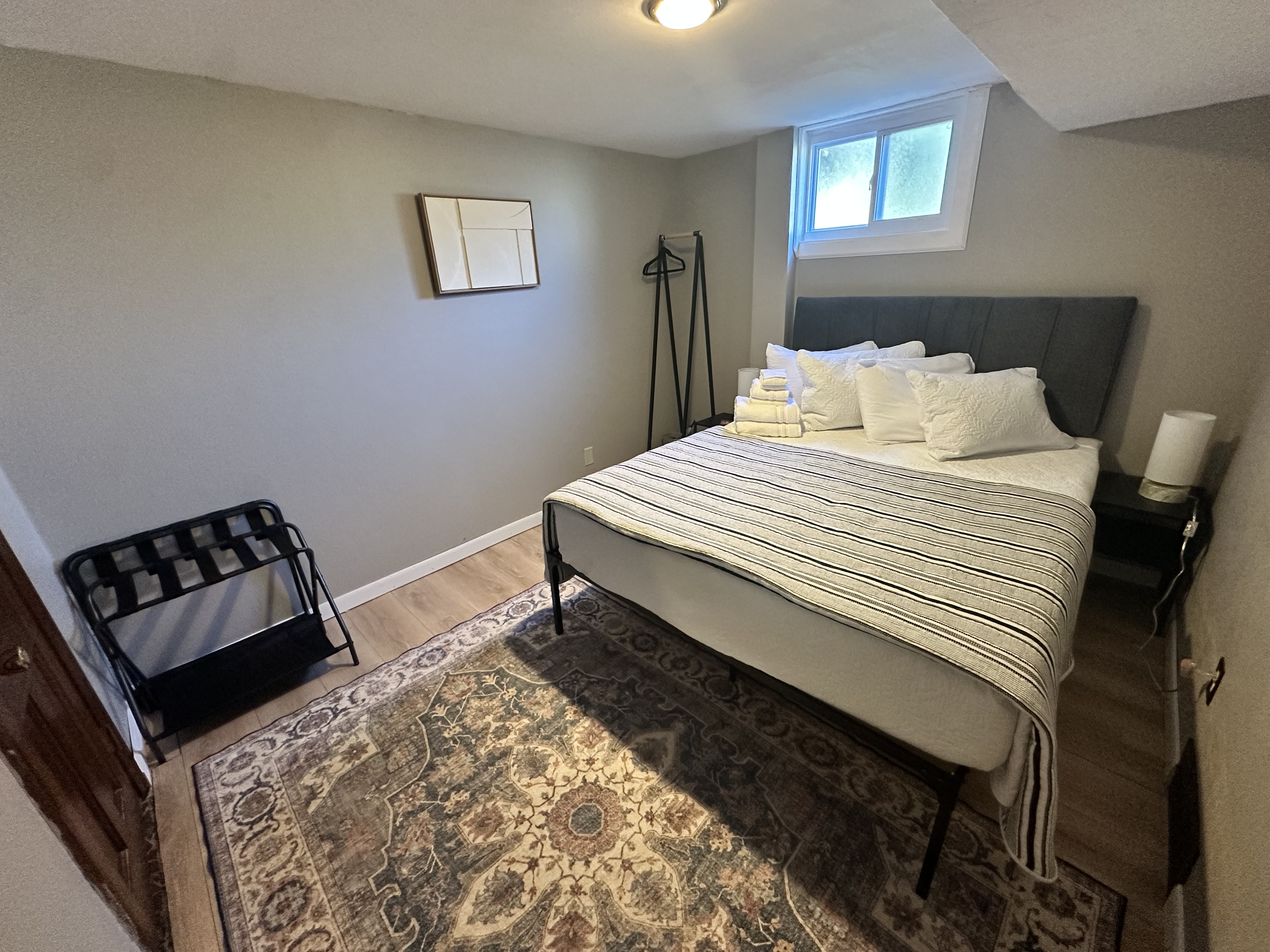 Cozy neutral bedroom with plush bedding, rug, and guest-friendly storage