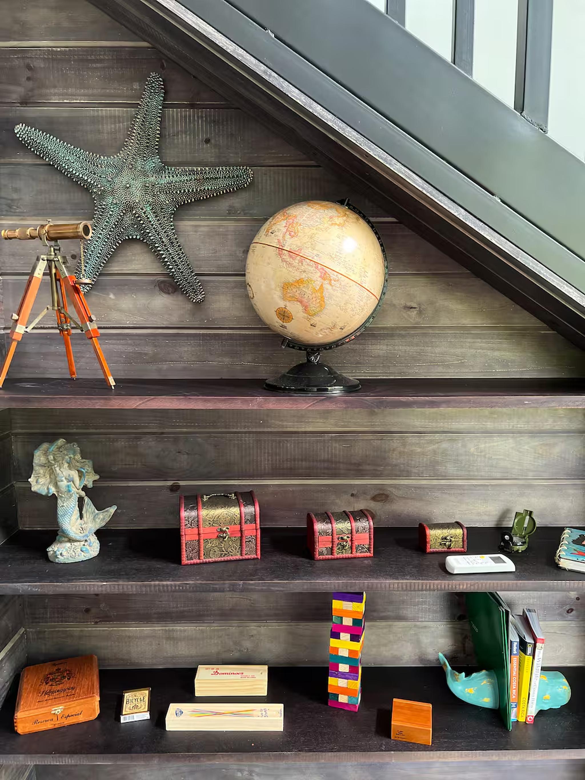 Curated under-stair shelving with coastal charm and vintage travel accents