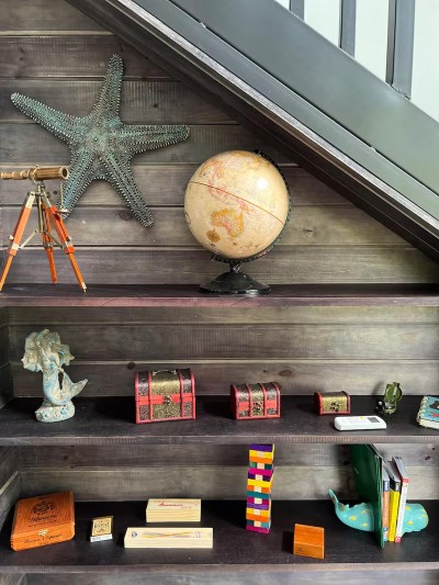 Curated under-stair shelving with coastal charm and vintage travel accents