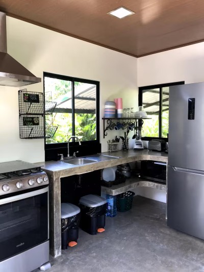 Bright tropical kitchen with full-size fridge, stove, and garden views