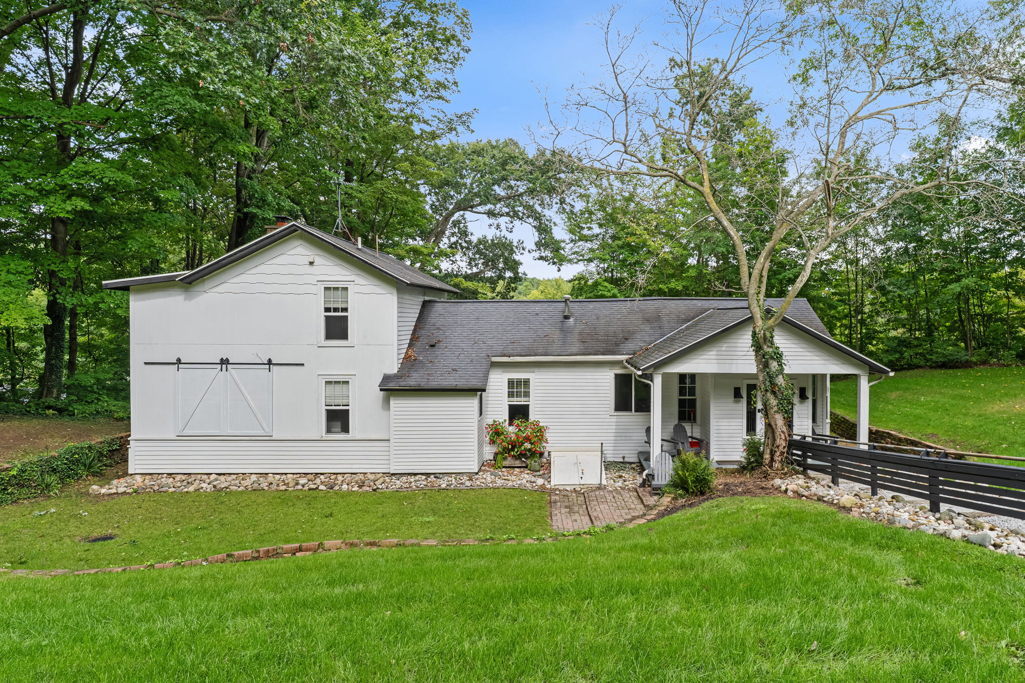 Charming wooded cottage with a covered porch and spacious green lawn