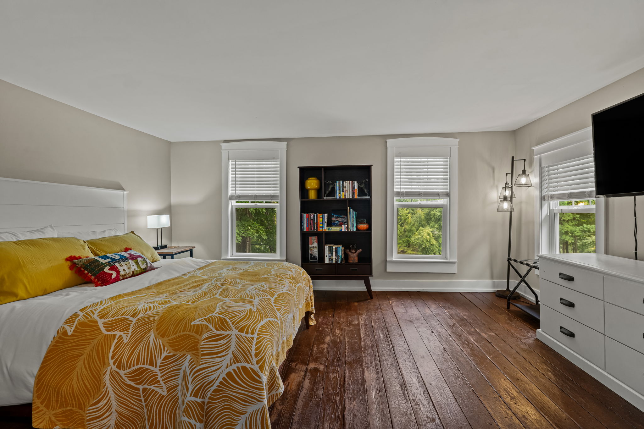 Bright, spacious bedroom with hardwood floors and peaceful leafy views