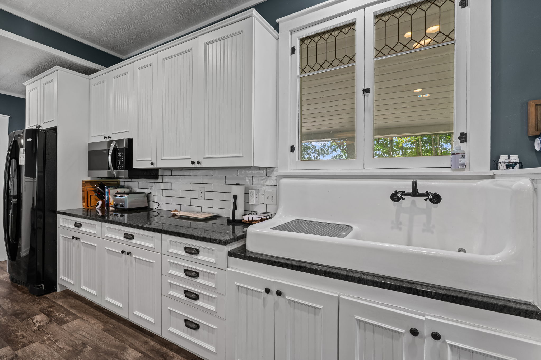 Bright kitchen with farmhouse sink, tall cabinetry, and elegant finishes