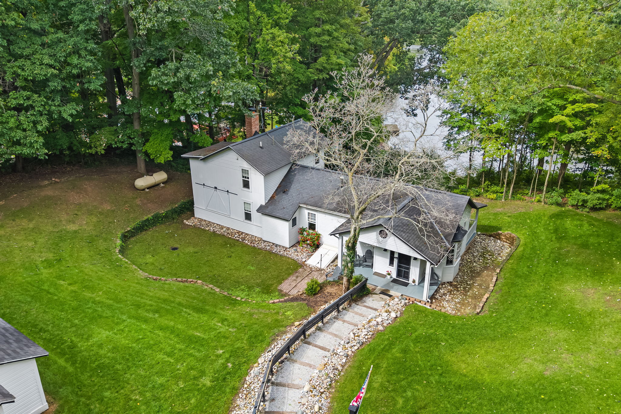 Charming wooded retreat with spacious lawn, porch, and water nearby