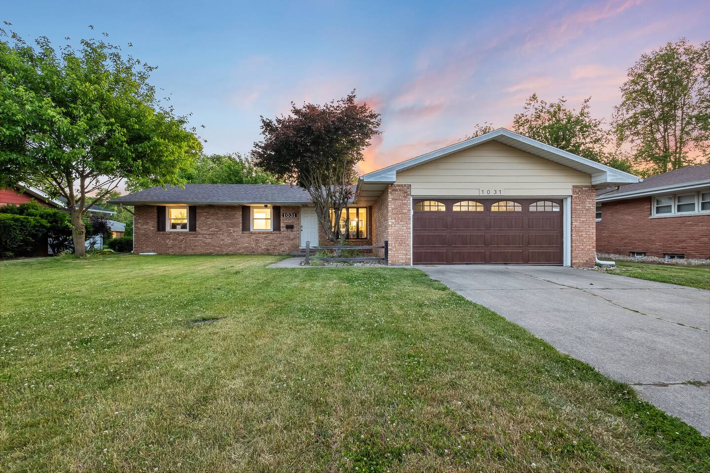 Brick ranch exterior with attached two-car garage at dusk