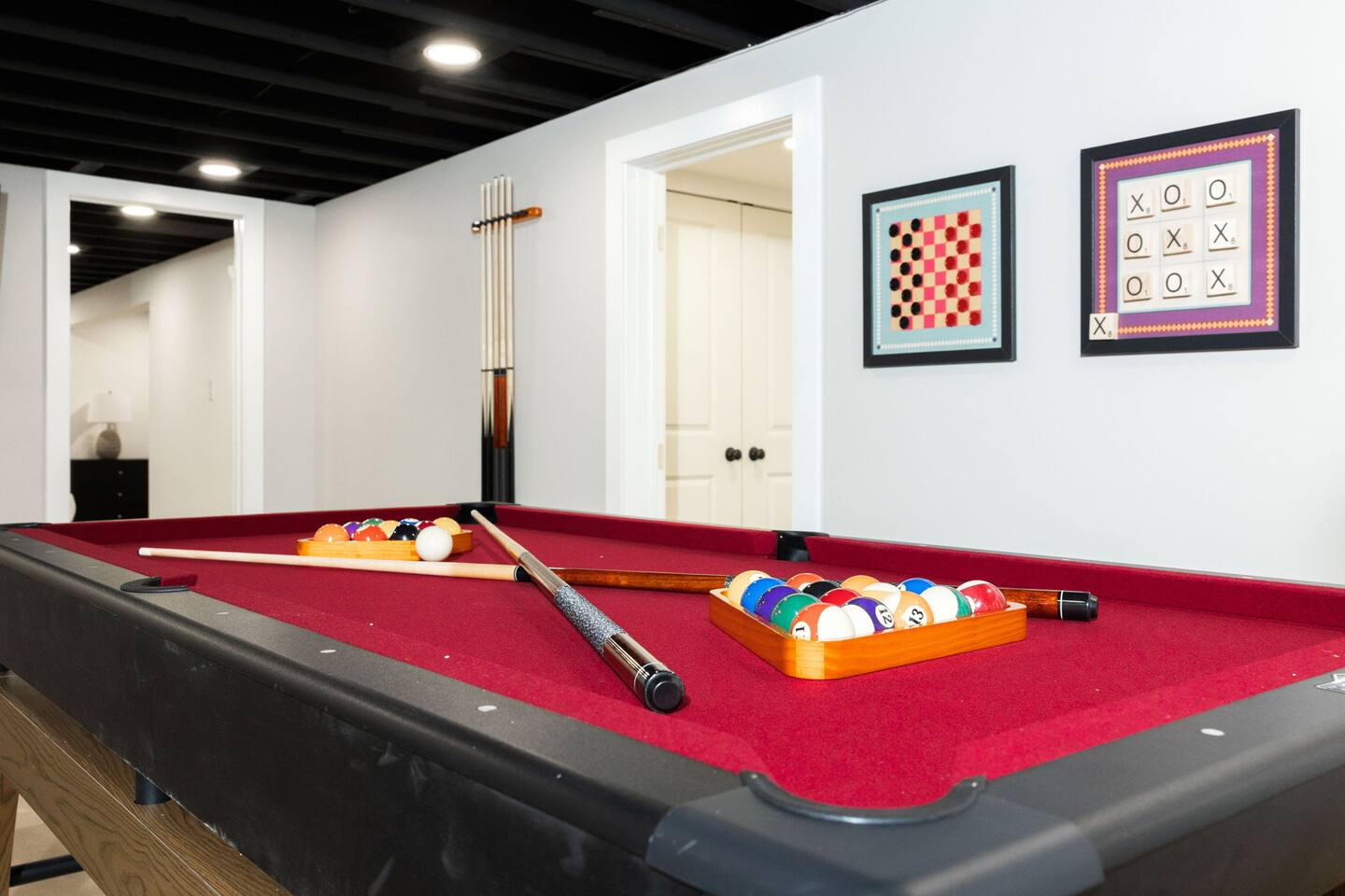 Red-felt 7-foot pool table with racked balls and cues