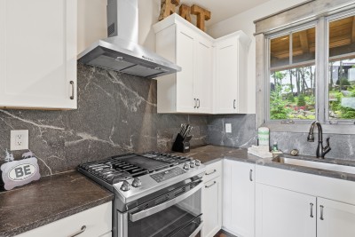 Bright modern kitchen featuring a gas range, stylish finishes, and lovely garden views — the perfect spot to cook while soaking in the scenery.