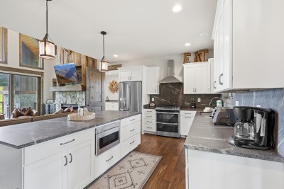 Bright open kitchen featuring a large island, stainless steel appliances, and rustic charm — stylish and inviting for cooking and gathering.