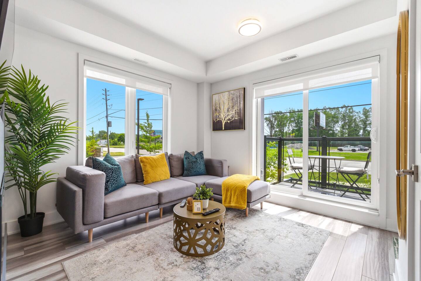 Bright living area with cozy seating, large windows, and balcony access, creating a relaxing space filled with natural light.
