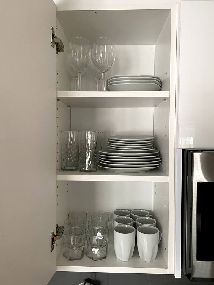 Kitchen cabinet stocked with plates, mugs, and glassware, making meals and drinks simple during your stay.