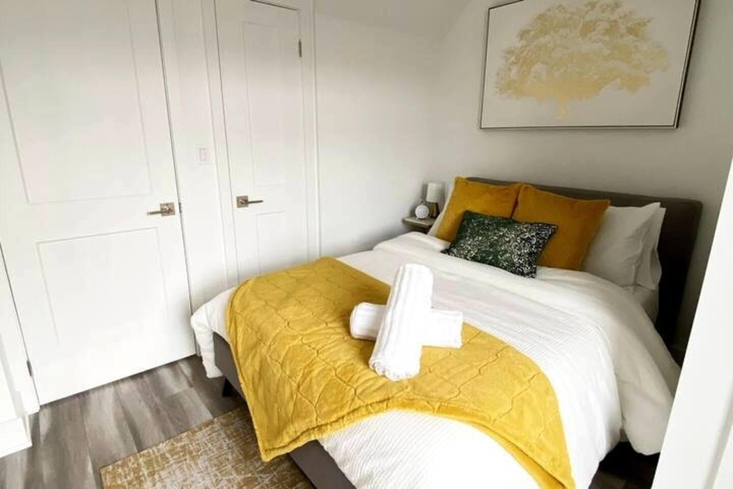 Comfortable bedroom with fresh linens, warm yellow accents, and bedside storage for a restful and practical stay.