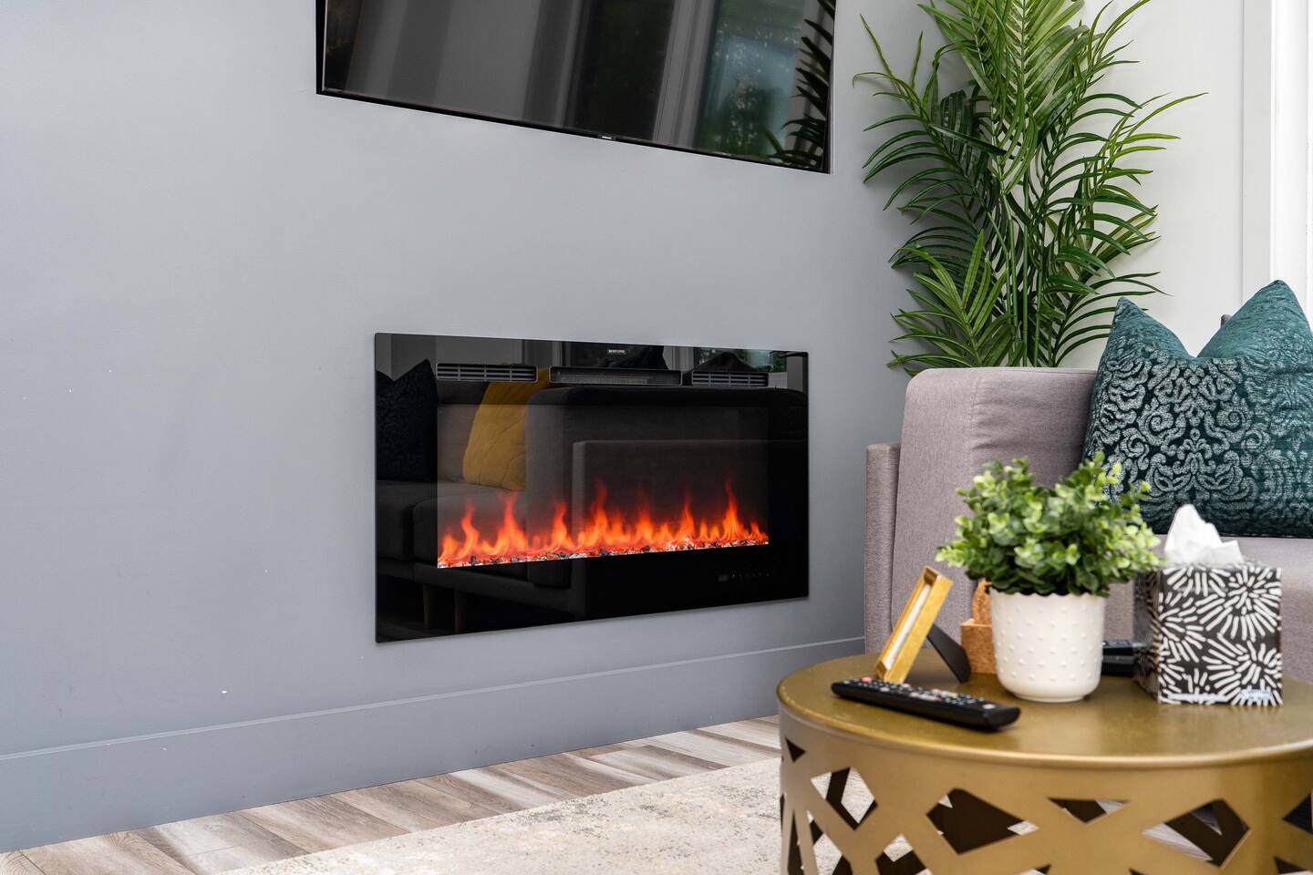 Wall-mounted fireplace with a TV above and cozy seating nearby, creating a warm and relaxing living room atmosphere.