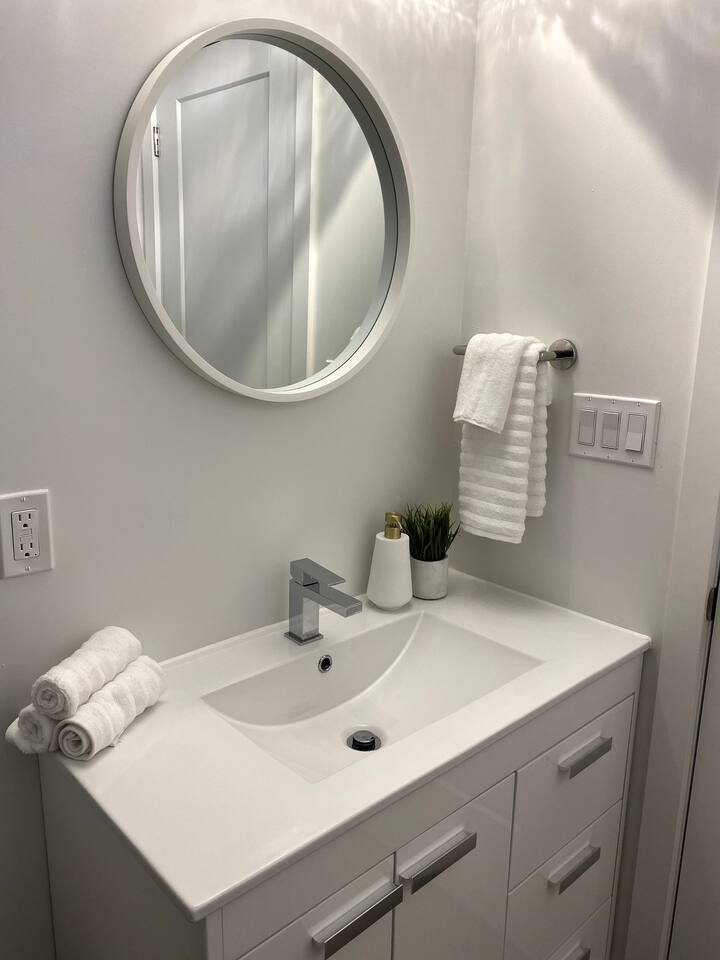 Modern bathroom vanity with a round mirror, fresh towels, and clean finishes for an easy, comfortable routine.
