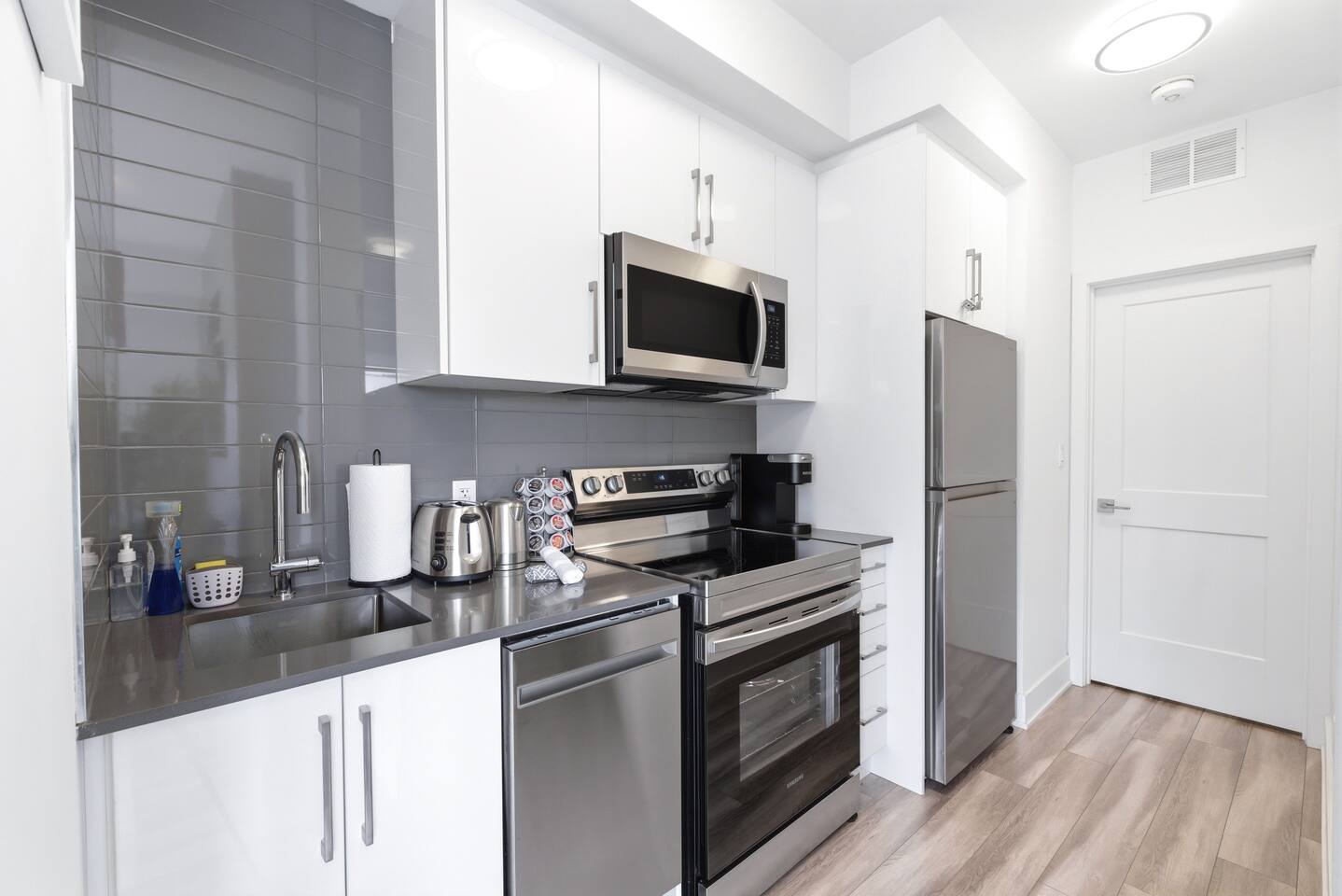 Modern kitchen with stainless appliances, sleek white cabinetry, and counter essentials, creating an easy space for cooking and daily convenience.