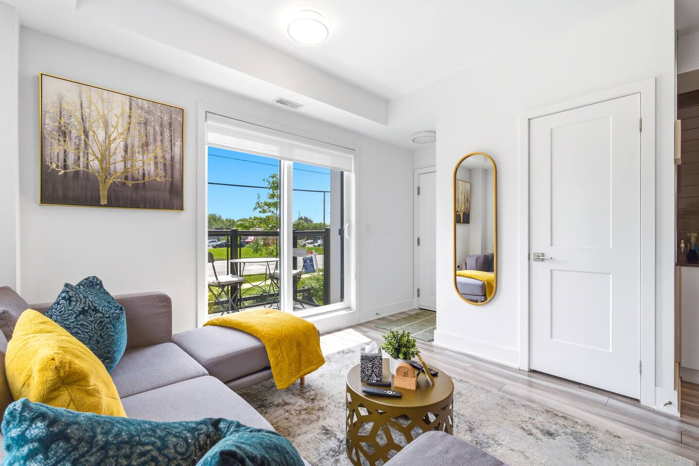 Bright living area with cozy seating, stylish decor, and balcony access, creating an inviting space to relax indoors or step outside for fresh air.
