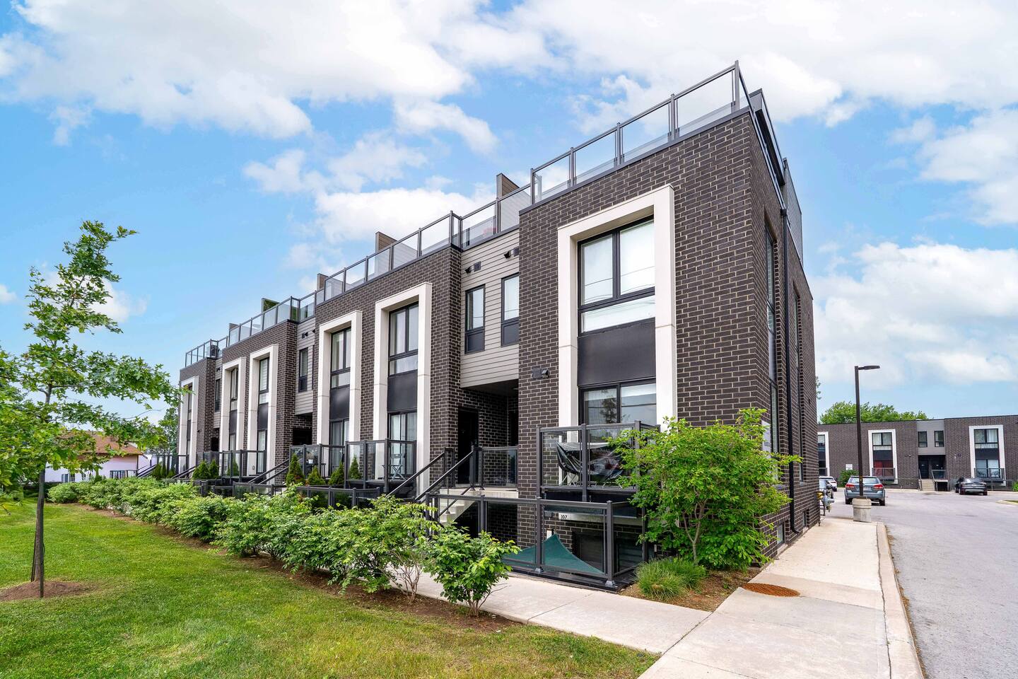 Modern townhouse exterior with landscaped greenery, private balconies, and a clean walkway, offering a welcoming first impression.