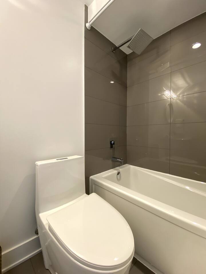 Clean bathroom with a tub and shower, modern tile surround, and bright lighting for a simple, comfortable daily routine.