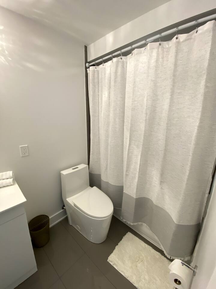 Simple bathroom with a clean vanity, modern toilet, and shower curtain, providing a fresh and practical space for daily routines.