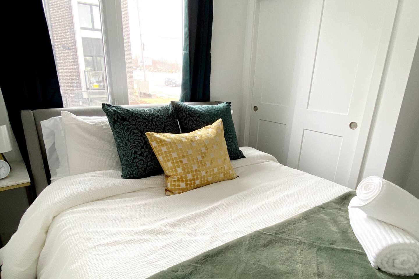 Close-up of the bed with layered pillows, fresh linens, and natural light, creating a clean and restful bedroom setting.