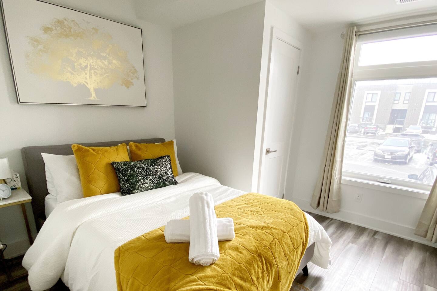 Bright bedroom with fresh linens, warm yellow accents, and natural light, offering a comfortable space to relax and recharge.