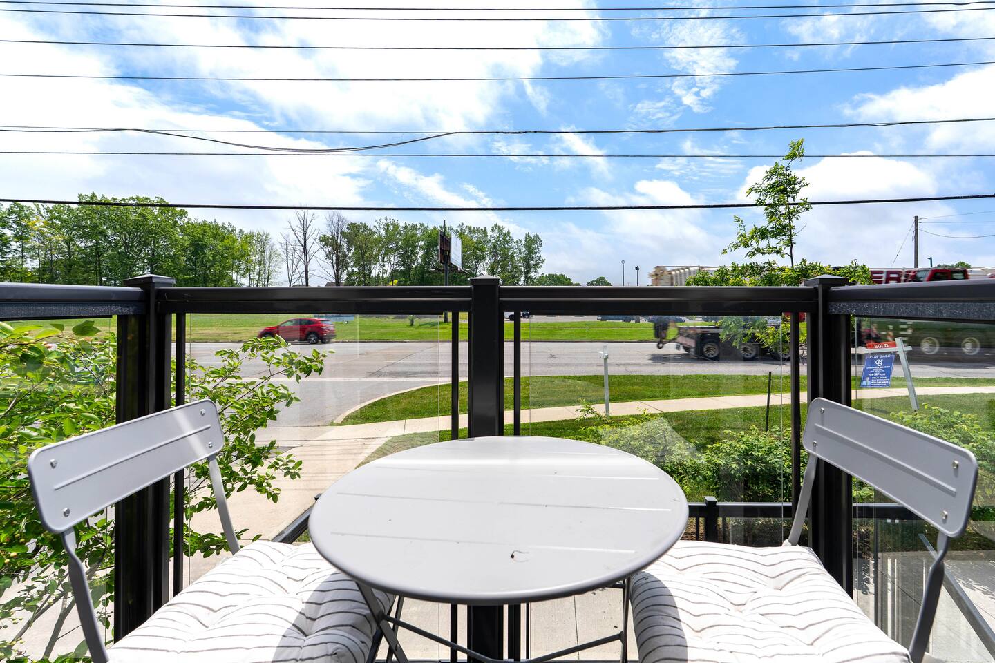 Private balcony with a small table, cushioned seating, and open green views, offering a bright spot to relax outside.