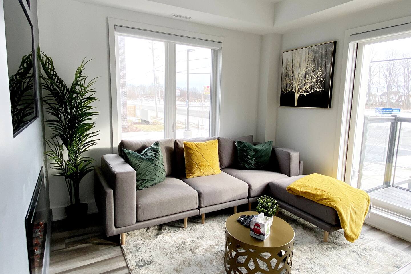 Cozy lounge with large windows, soft seating, and warm accents, offering a comfortable space to relax with natural light and city views.