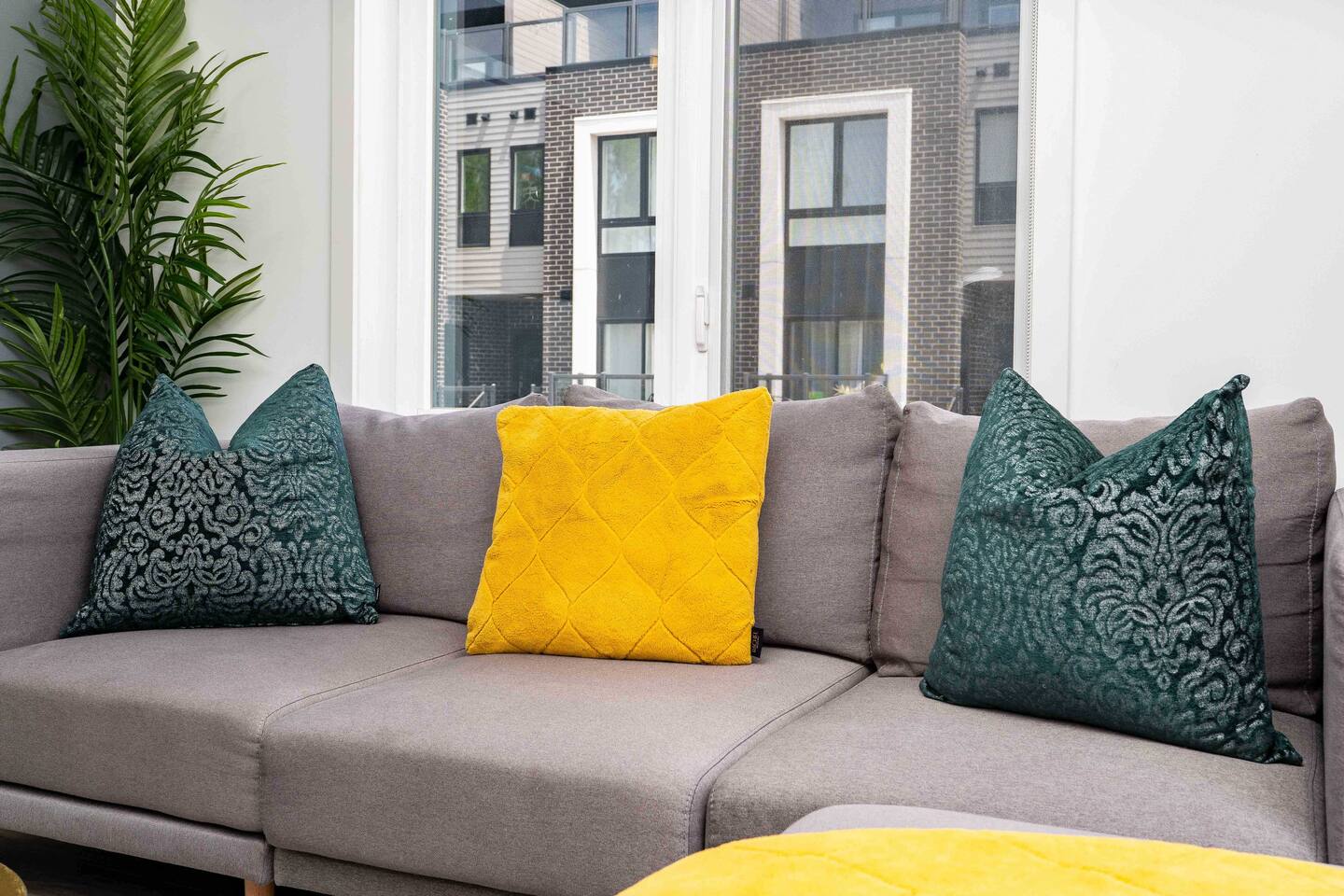 Bright living space with a comfortable sofa, colorful pillows, and large windows, creating a relaxed spot to sit and enjoy natural light.