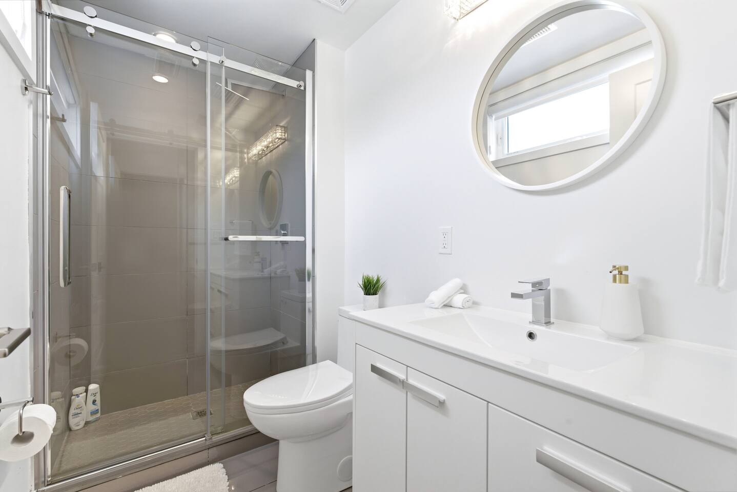 Bright bathroom with a walk-in glass shower, clean vanity, and fresh towels, offering a simple and comfortable space to refresh.