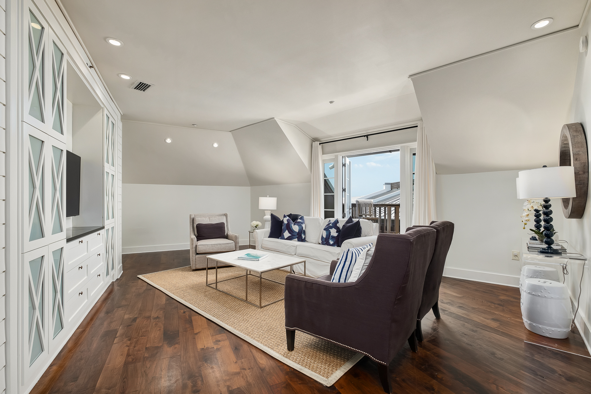 Bright top-floor living room with hardwood floors and balcony access
