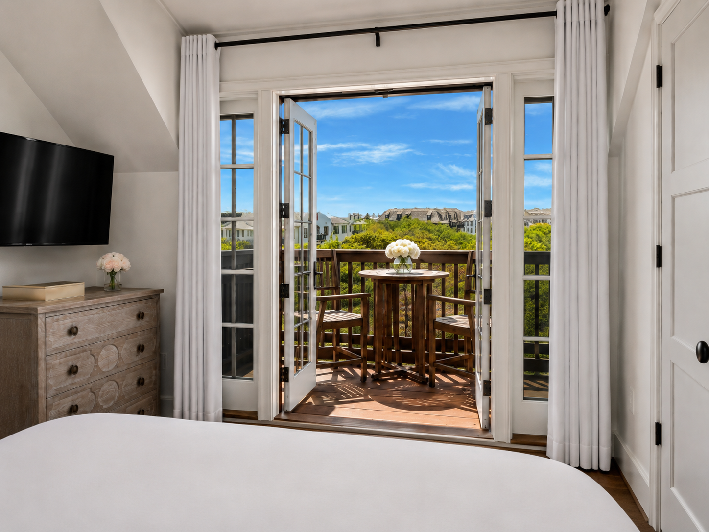 Bright bedroom with French doors to a private balcony and views of the town