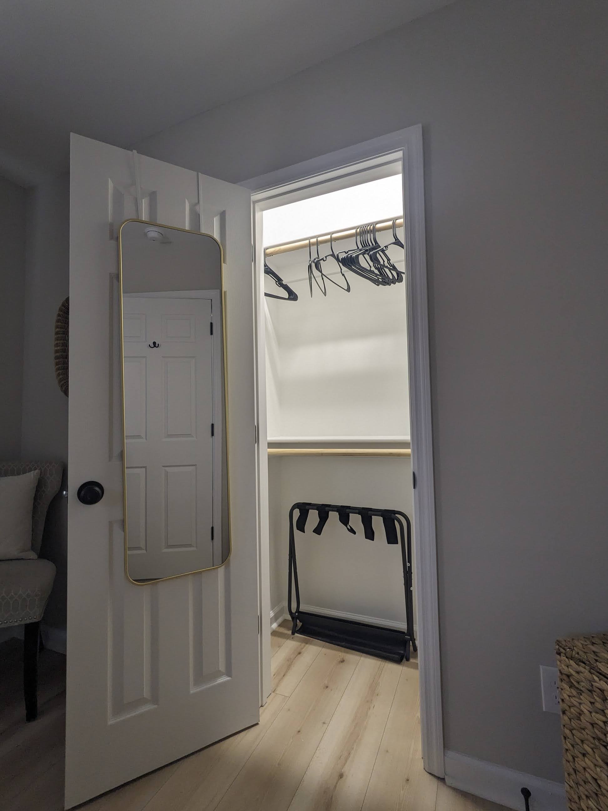 Bright walk-in closet with full-length mirror and luggage rack