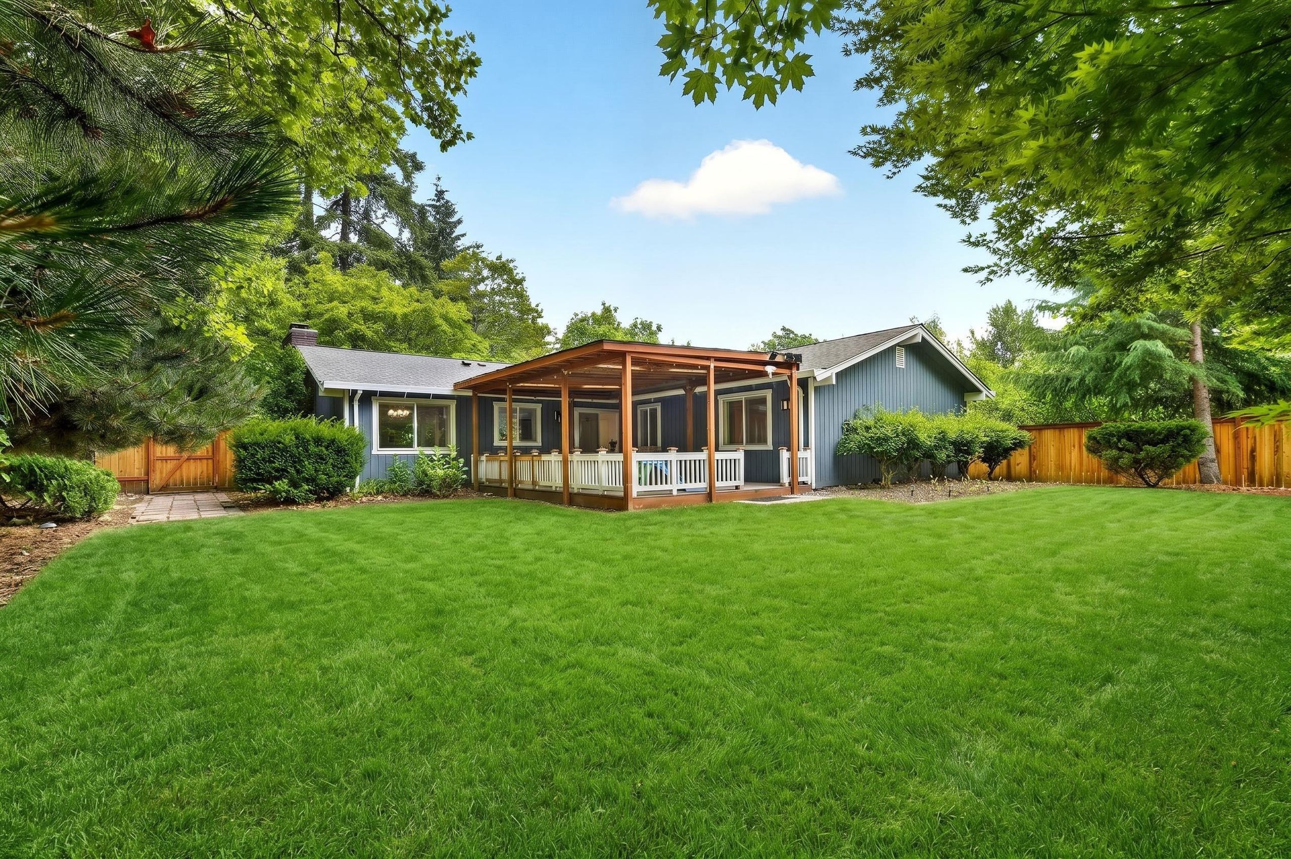 Spacious fenced backyard with lush lawn and covered patio retreat