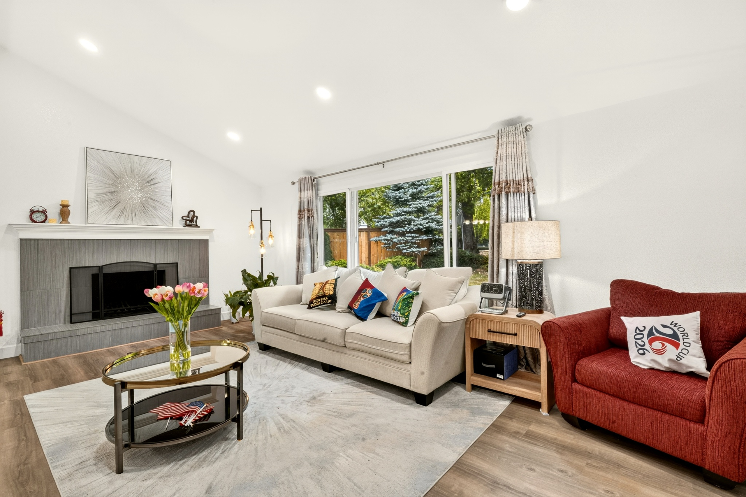 Bright, cozy living room with fireplace and large garden-view window