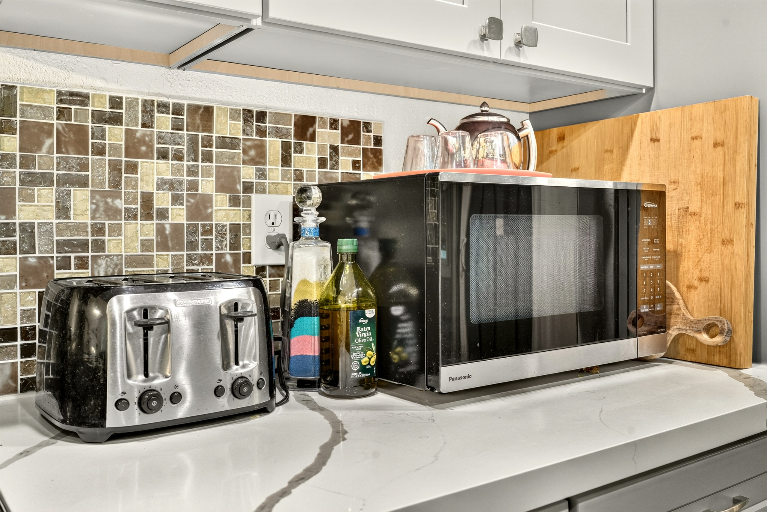 Modern kitchen setup with microwave, toaster, and stylish tile backsplash